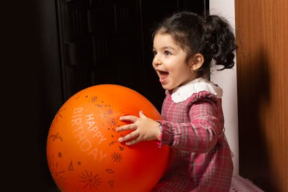 Girl holding balloon indoors