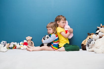 two children back to back and surrounded by toys
