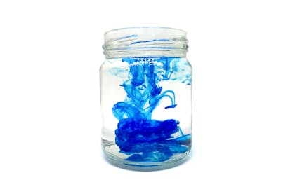 Clear glass jar with blue food colouring and water 