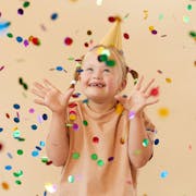 Young girl wearing party hat amid confetti