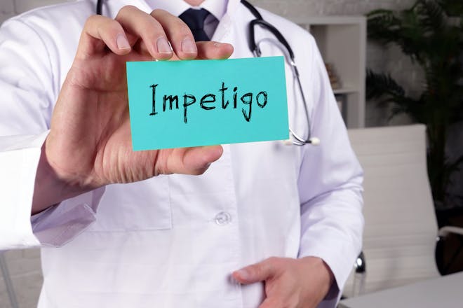 Man holding card saying Impetigo 