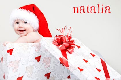 Baby wearing a Santa hat and popping out of a big gift box with a red bow