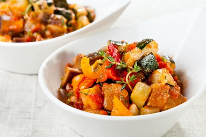 Vegetable goulash with courgettes, tomatoes and peppers in a white bowl