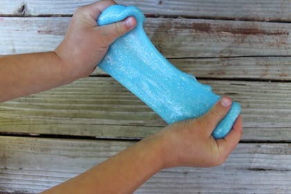 Child's hands playing with blue glitter slime