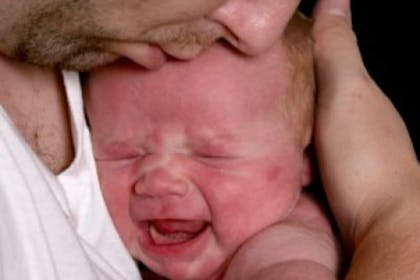 man hugging crying baby