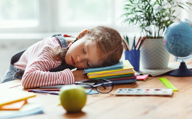 Young girl with her head on the desk, asleep on some books