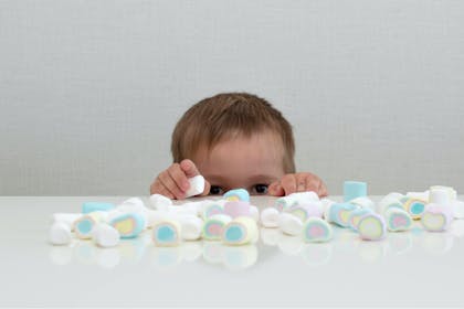 Toddler placing lots of marshmallows on the table 