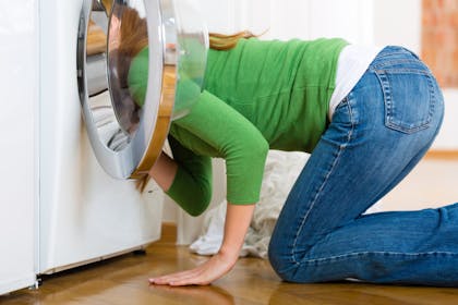 woman looking in washing machine searching for something