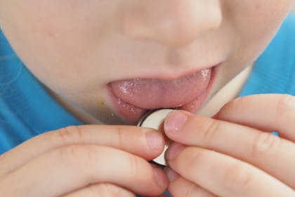 child putting button battery in mouth