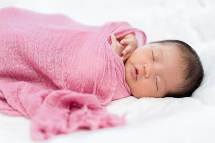 baby wrapped in pink muslin