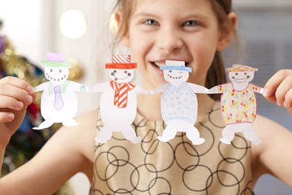 Girl holding paper chain of snowmen