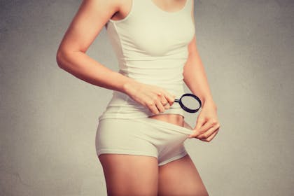 Woman looking in her knickers with magnifying glass
