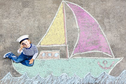Child sitting on chalk drawing of boat