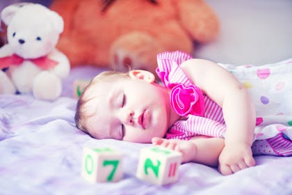 Toddler sleeping with teddies and blocks