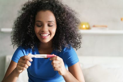 smiling woman holding pregnancy test