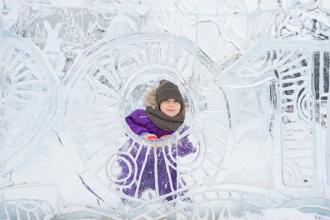 A kid looks through a hole in an ice sculpture