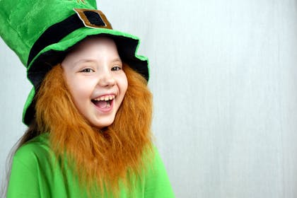 Kid dressed as leprechaun with green top hat, green t-shit and fake ginger beard