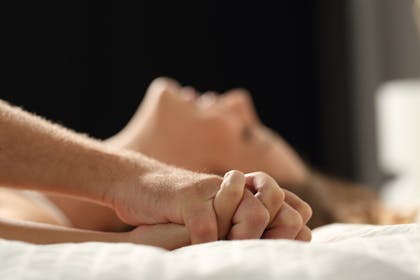 couple clenching hands on bed sex