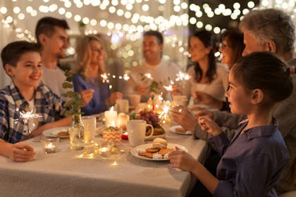 Kids joining in at a family dinner party with lights and sparklers