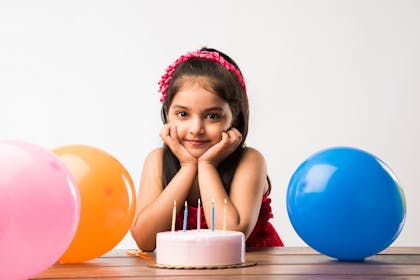 Girl in front of 5-year-old birthday cake