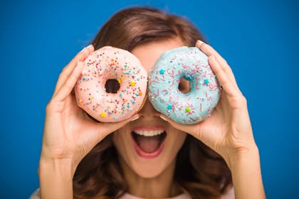 Woman holding doughnuts over eyes