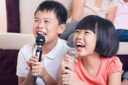 Two kids singing into karaoke microphones