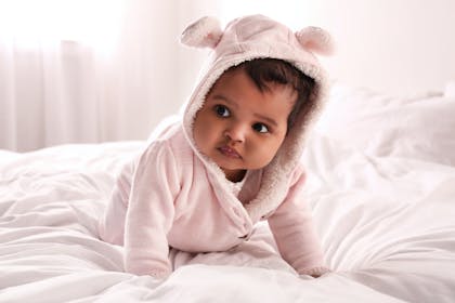 Baby crawling and wearing pink onesie 