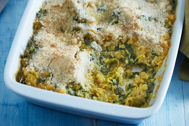 Lentil and spinach bake in a white tray with ground almond topping