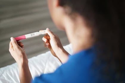 Woman sits holding negative pregnancy test