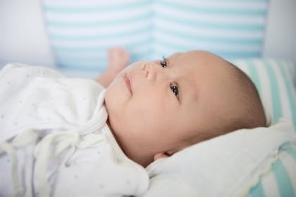 Young baby lying on their back opening eyes