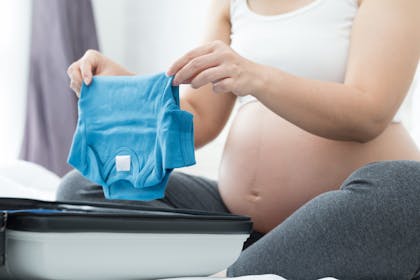 Pregnant woman packing suitcase for hospital