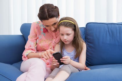 Girl and mum looking at phone on sofa