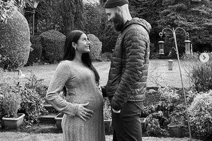 Pregnant woman and man stand in garden