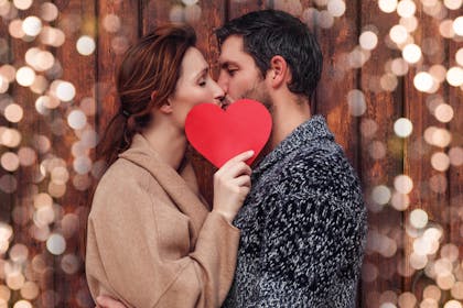 Couple kissing behind a red heart