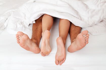 Man and woman's feet sticking out of duvet
