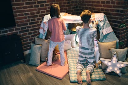 Boy and girl making a den in living room for a sleepover