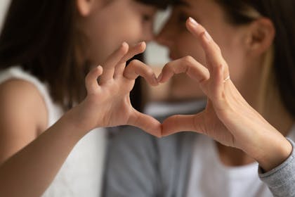 Mum and daughter making a heart with their fingers