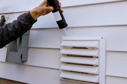 Man putting caulk around vent