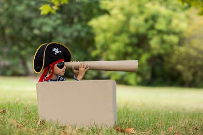boy sitting in a box in the park dressed as a pirate