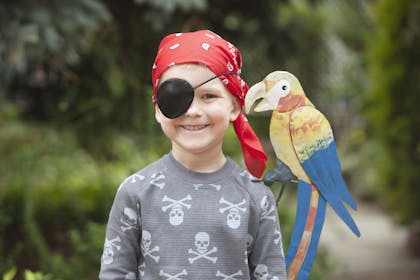 Boy dressed as pirate with parrot on his shoulder