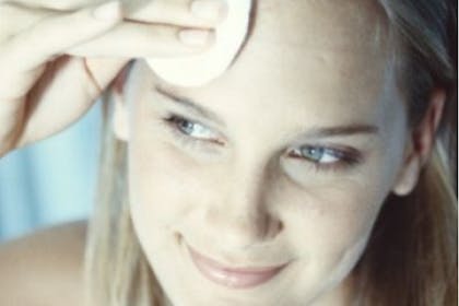 woman wiping face with cotton pad