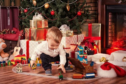 Little boy playing with toy near Christmas tree