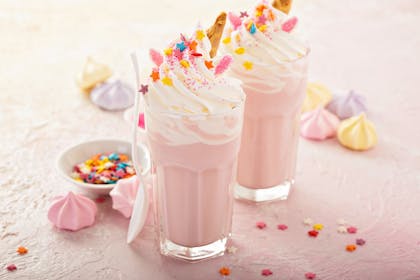 Pink milkshakes with sprinkles and a unicorn horn stuck in