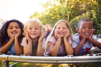 Group of kids lie on trampoline in garden