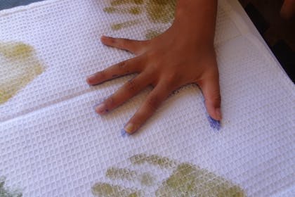 Child making handprints on a towel