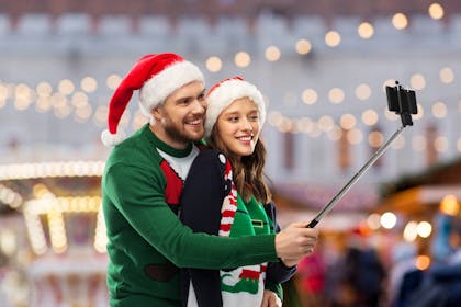 Couple wearing Santa hats holding a selfie stick
