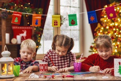 Children drawing with christmas tree in background