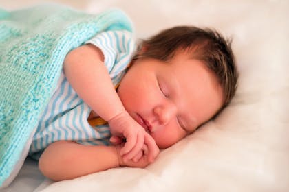 Baby sleeping wrapped up in knitted blanket 