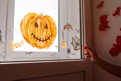 Picture of Halloween pumpkin, broomstick, spider's web and bats painted onto window