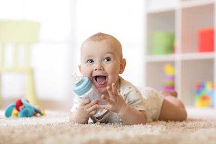 Excited baby lying on front holding bottle